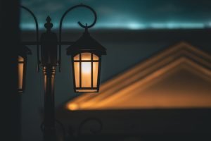 A warm, illuminated street lamp against a soft-focus architectural background creates a captivating night scene.