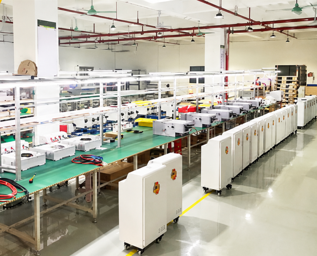A panoramic view of a well-established manufacturing workshop with over a decade of operational history. The spacious facility features a mature, highly organized layout with long assembly lines and active production zones. Rows of standard manufacturing equipment, overhead lighting systems, and clearly marked safety pathways demonstrate years of optimized factory management and industrial expertise.